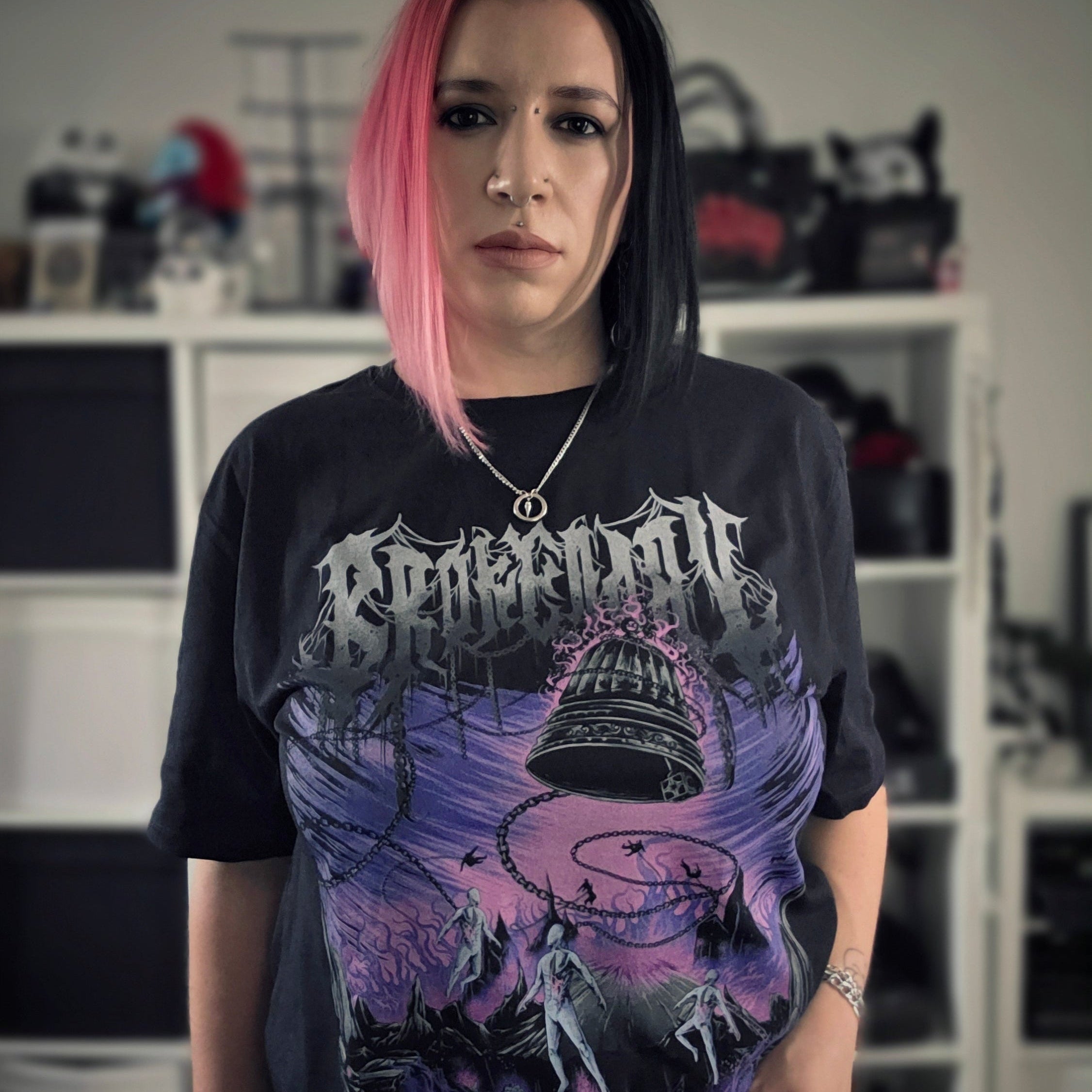 Person wearing a black t-shirt with a graphic design, standing indoors.