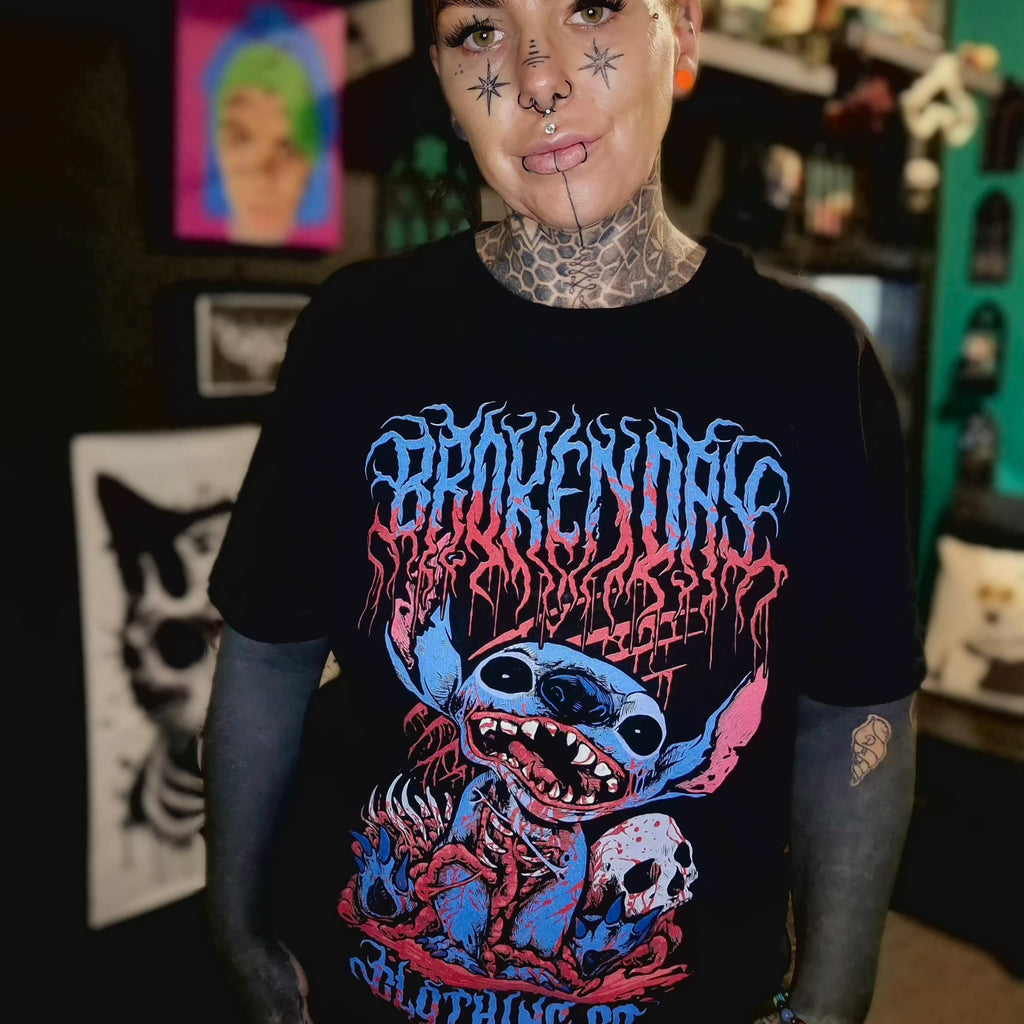 Person wearing a black t-shirt with colorful graphic design in a room with various items on shelves.