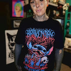 Person wearing a black t-shirt with colorful graphic design in a room with various items on shelves.