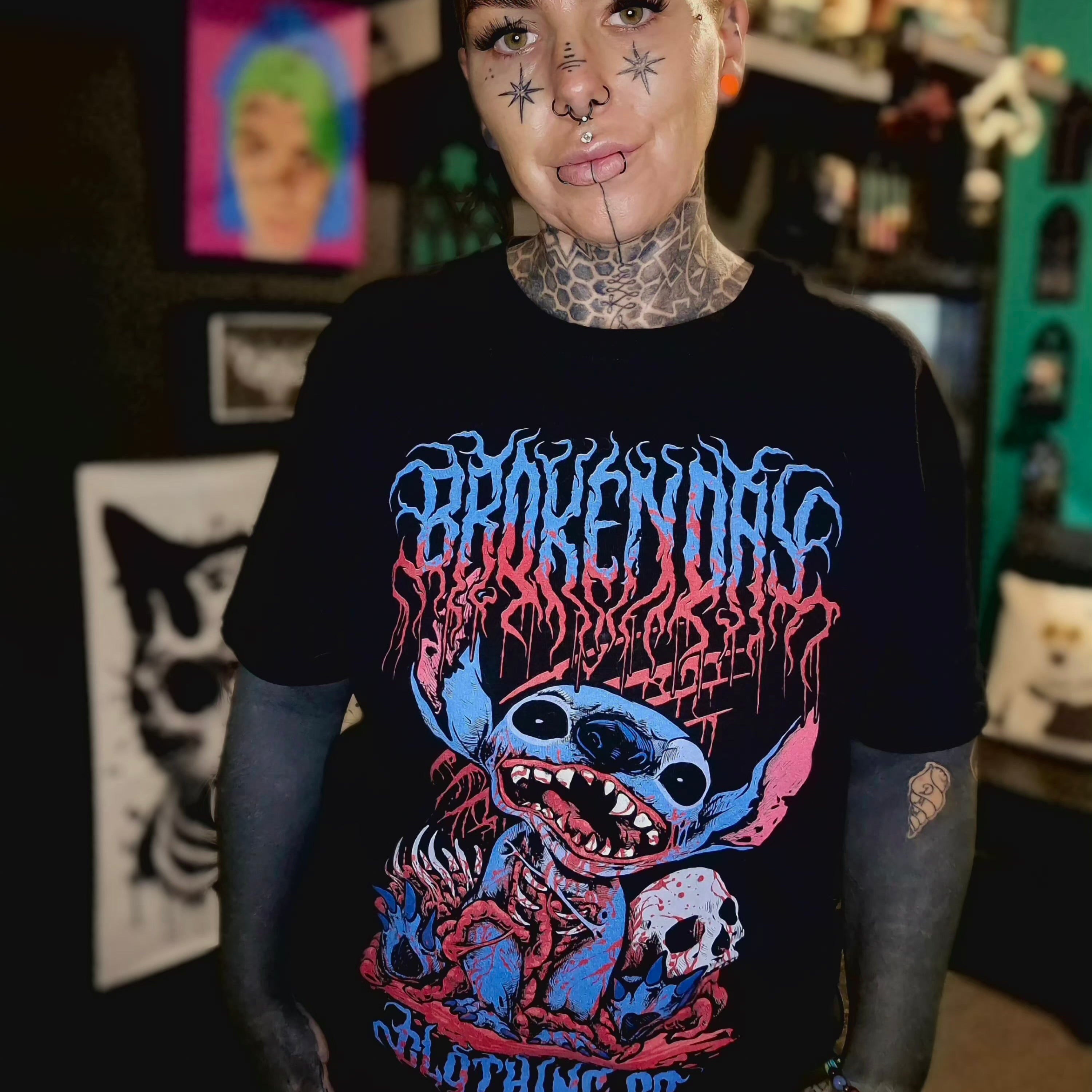 Person wearing a black t-shirt with colorful graphic design in a room with various items on shelves.