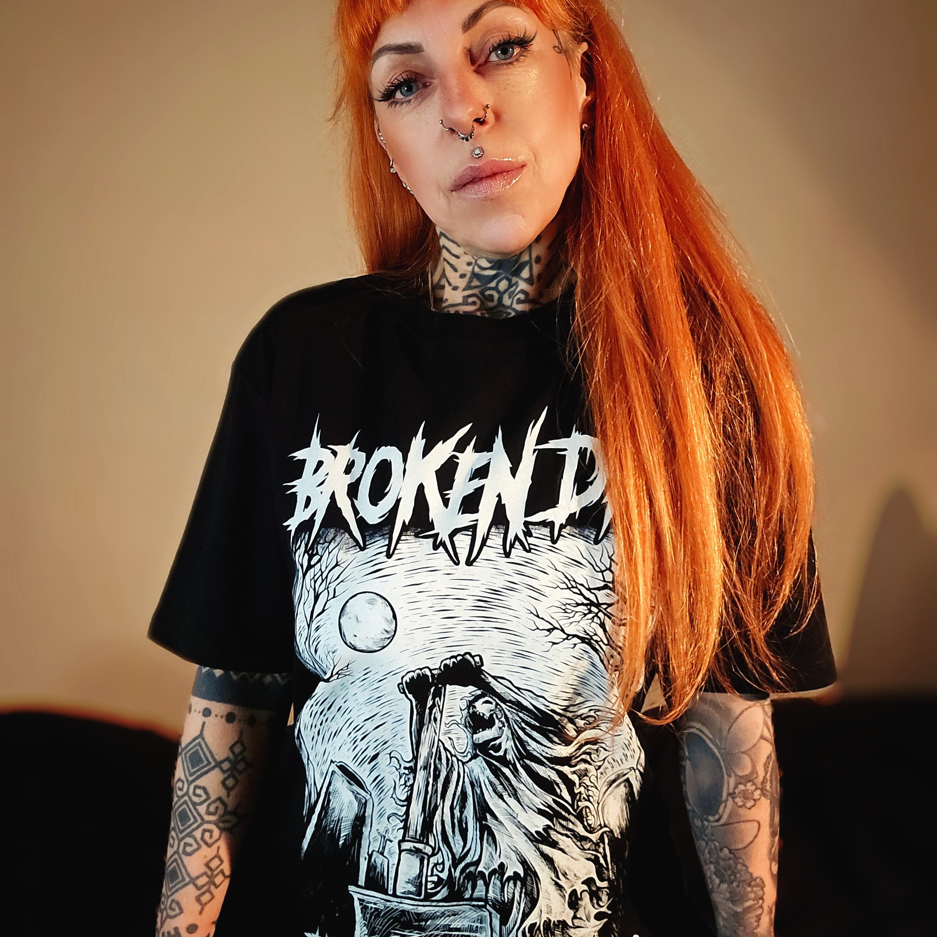 A person wearing a black crew neck t-shirt with a graphic print of a character and the text 'BROKEN', and the phrase 'There's blood on your hands' printed on the front.