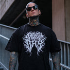 Man wearing a black t-shirt with a white graphic design, standing against an urban background.