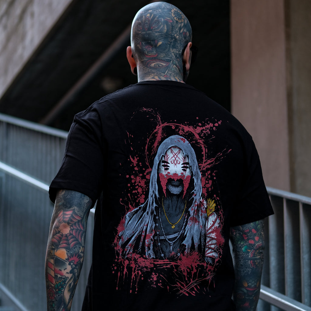 Person wearing a black t-shirt with a graphic design on the back, standing outdoors.